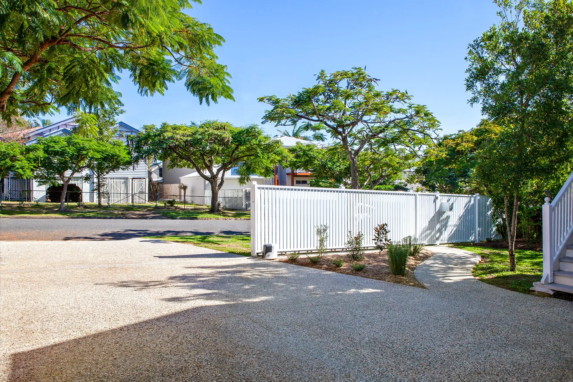 Close-up view of a driveway renovation in Hawthorne, showcasing exposed aggregate, a matching pathway, and a white electric gate that complements the home’s banister and entrance.