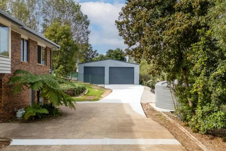 View from house showing driveway leading to caravan and boat storage shed with twin roller doors.