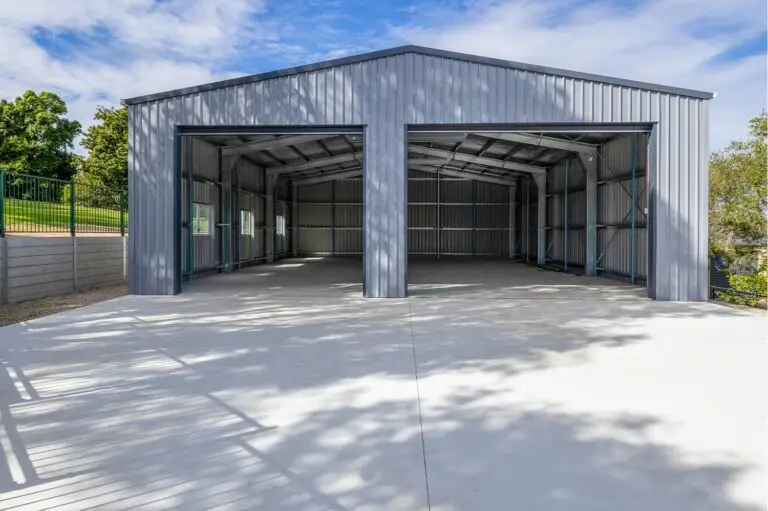 Open roller doors reveal interior of a caravan and boat storage shed with clean concrete slab and COLORBOND® Bluegum walls.
