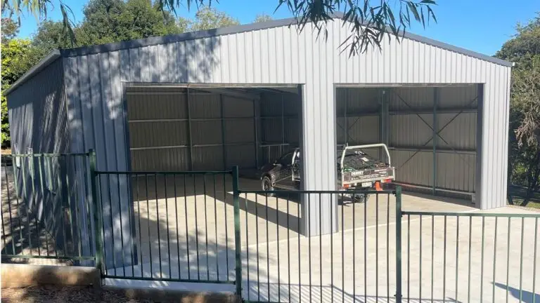 Partially completed caravan and boat storage shed with open roller doors and a ute parked inside.