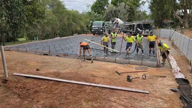 Debret crew pouring concrete slab for caravan and boat storage shed with retaining wall in background.
