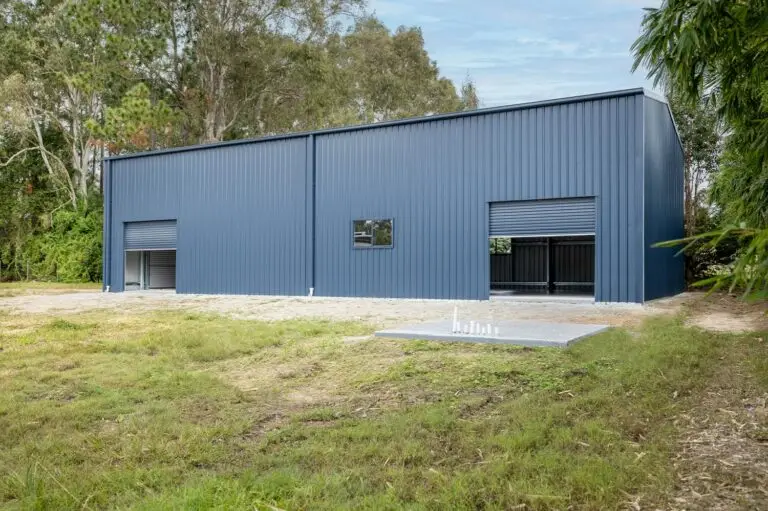 Side view of workshop shed in Forestdale with roller doors, windows, and matching watertank slab