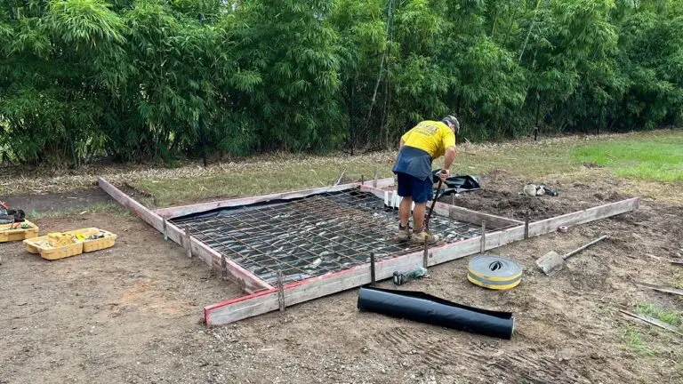 Debret team prepping small slab for watertank beside workshop shed